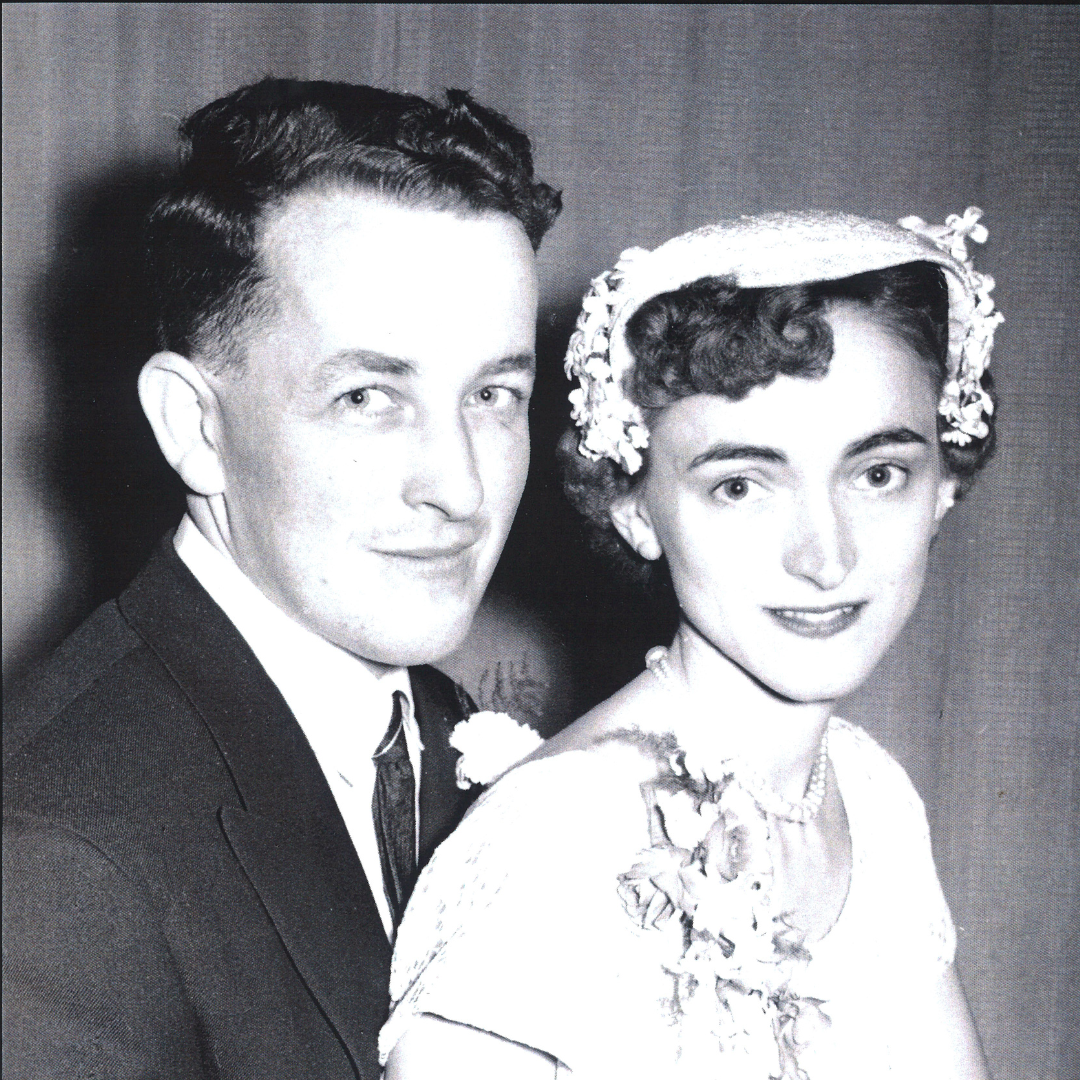 A black-and-white wedding photo from 1957 of John and Lorene Donaldson. John wears a dark suit with a boutonnière, and Lorene wears a floral headpiece with a short veil and a corsage on her dress.